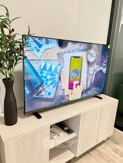 Modern living room with sleek TV on stylish wooden stand and decorative plant, showcasing contemporary interior design.