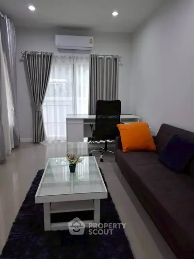 Modern living room with sleek furniture and natural light, featuring a cozy sofa and stylish desk.