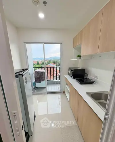 Modern kitchen with sleek cabinetry and balcony view in a stylish apartment