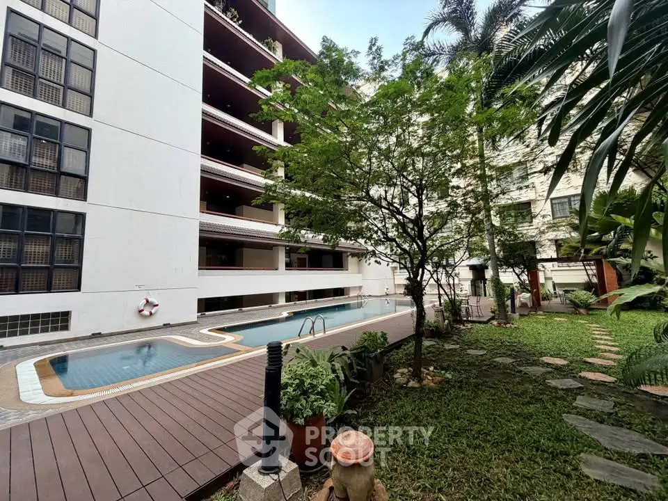 Luxurious apartment complex with pool and lush garden, perfect for relaxation and leisure.