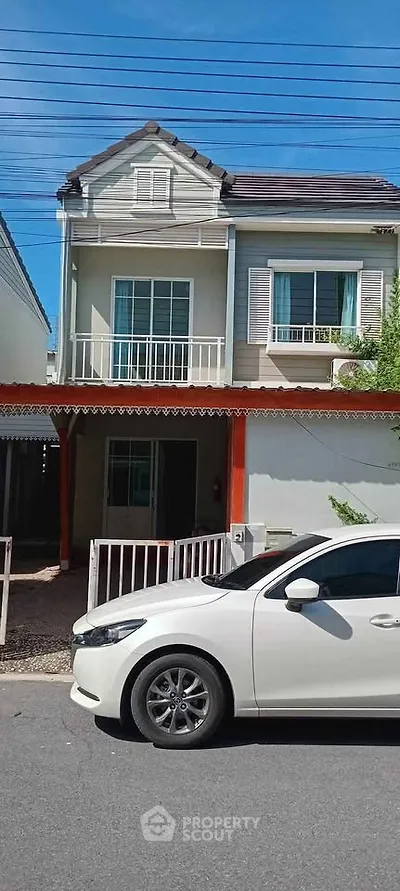Charming two-story house with balcony and driveway in a suburban neighborhood.