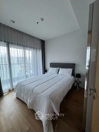 Modern bedroom with large windows and city view, featuring a cozy bed and elegant decor.