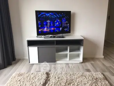 Modern living room with sleek TV stand and flat-screen TV on stylish wooden flooring.