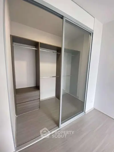 Spacious modern walk-in closet with sliding doors and sleek wooden finish.