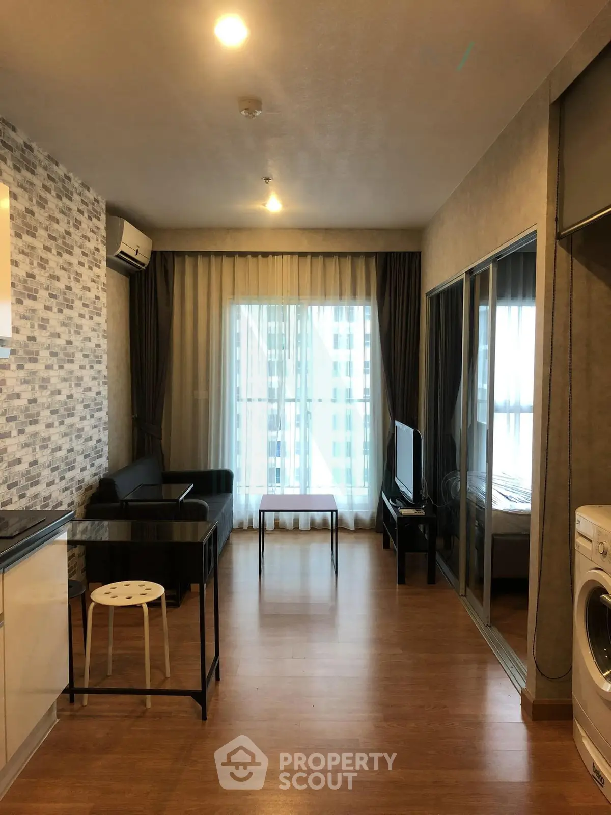 Modern apartment interior with open layout, featuring a cozy living area and kitchen with washing machine.