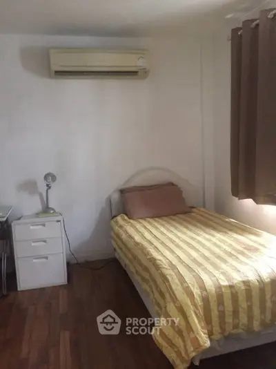 Cozy bedroom with single bed, air conditioning, and wooden flooring, perfect for a comfortable living space.