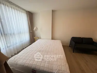 Spacious bedroom with large window and cozy seating area, perfect for relaxation.