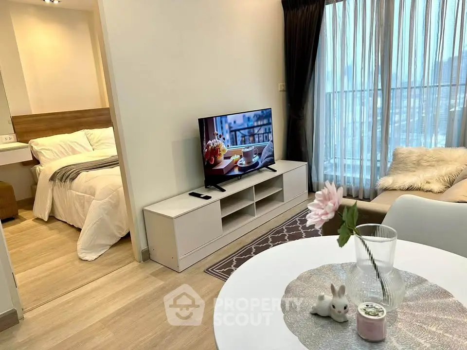 Modern living room with cozy decor and open view to bedroom, featuring stylish furniture and natural light.