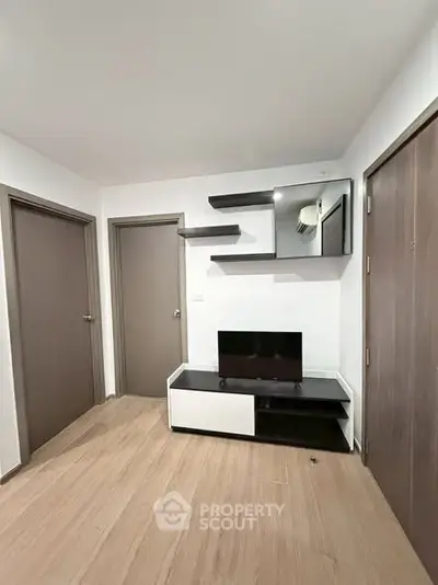 Modern living room with sleek TV stand and wall shelves, featuring minimalist design and wooden flooring.