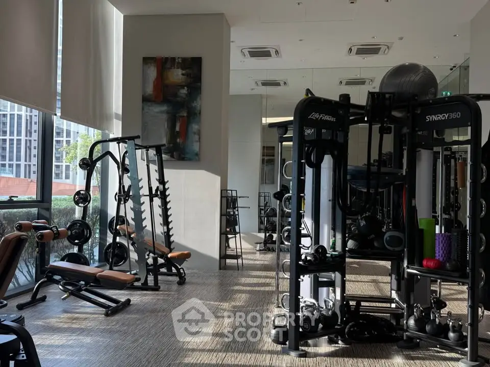 Modern gym with state-of-the-art fitness equipment and large windows offering natural light.