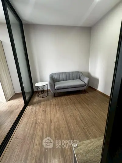 Cozy small living room with modern gray sofa and wooden flooring