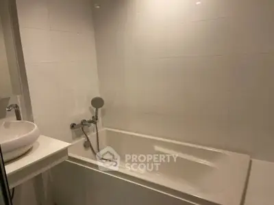 Modern bathroom with sleek white tiles and a built-in bathtub, perfect for relaxation.
