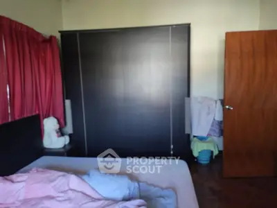 Cozy bedroom with dark wardrobe and pink curtains, perfect for relaxation.