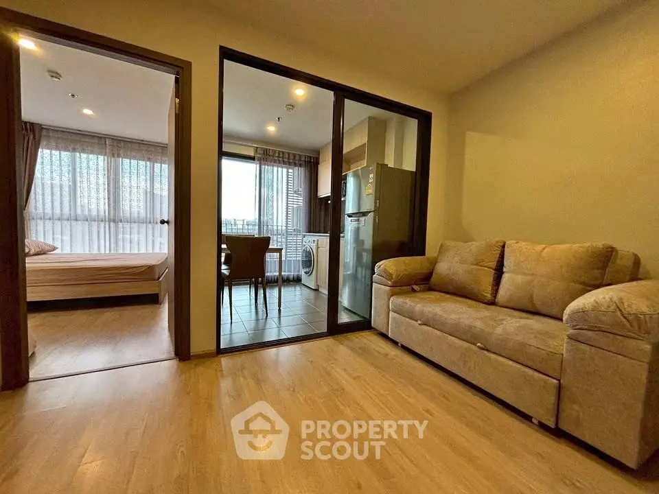 Modern apartment interior with cozy living room and adjacent kitchen area, featuring a washing machine.