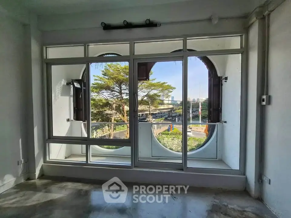 Spacious room with unique circular windows offering a scenic view, perfect for modern living.