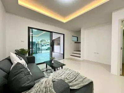 Modern living room with sleek design and cozy ambiance, featuring a stylish sofa and large sliding glass doors.