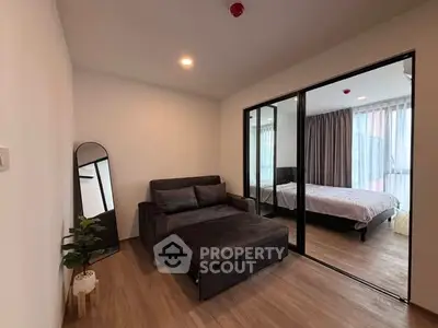 Modern apartment with cozy living room and bedroom, featuring sleek furniture and large windows.