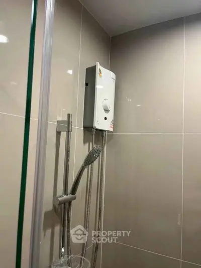 Modern bathroom with sleek shower and water heater in contemporary apartment.