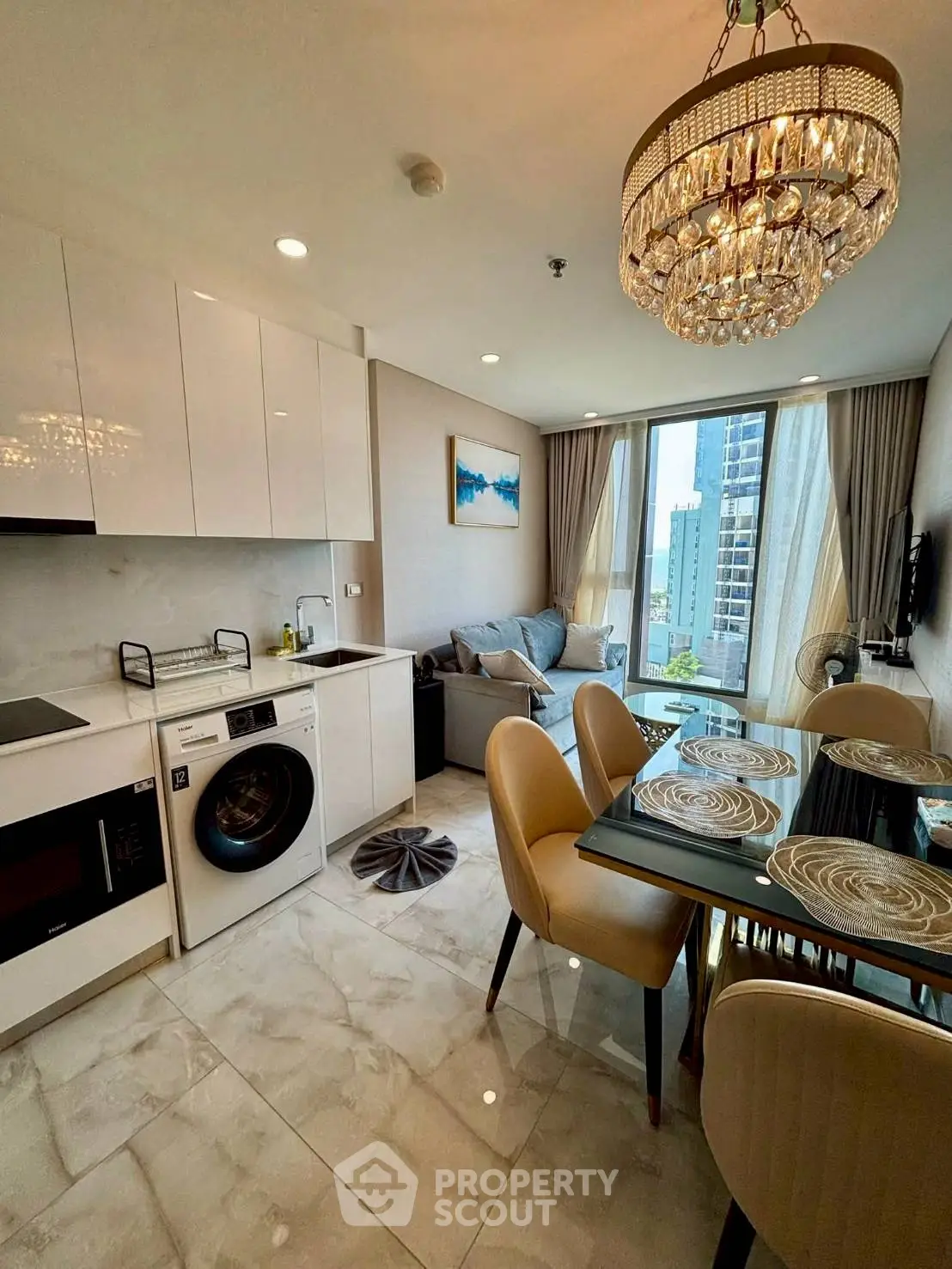 Luxurious modern living room with open kitchen, elegant chandelier, and city view.