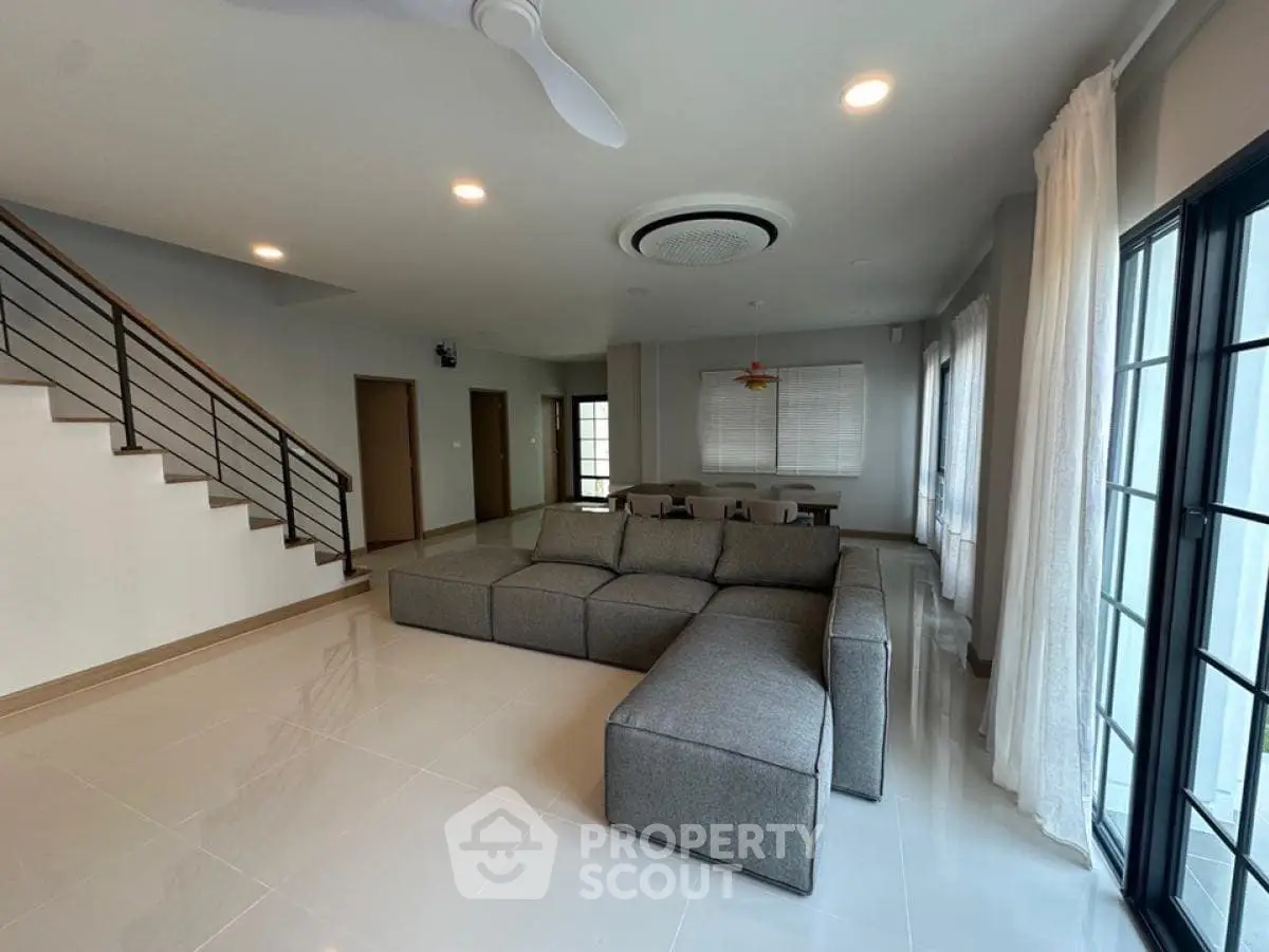Spacious modern living room with sleek sectional sofa and large windows for natural light.