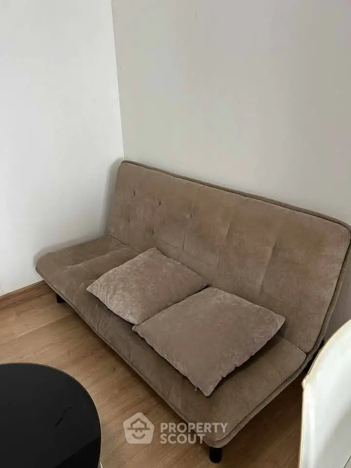 Cozy living room corner with a beige sofa and wooden flooring