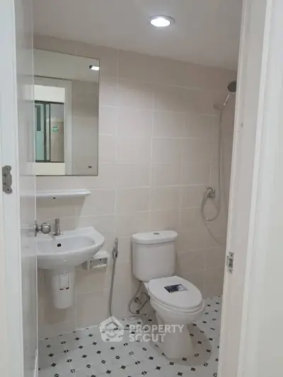 Modern bathroom with sleek fixtures and neutral tiles, featuring a shower and toilet.