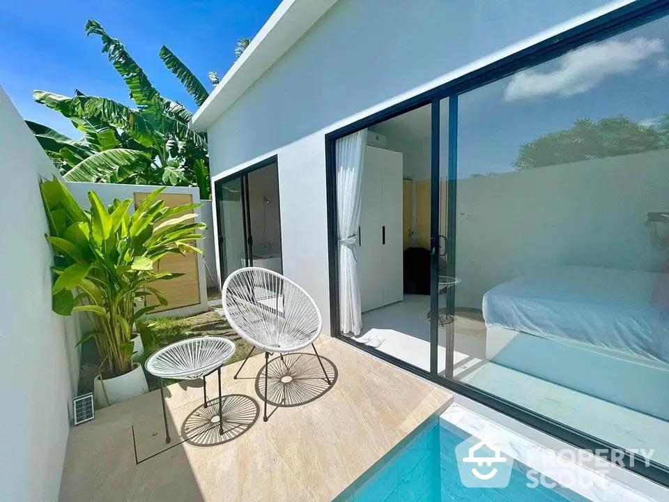 Modern villa with private pool and lush garden, featuring sleek sliding glass doors and stylish outdoor seating.