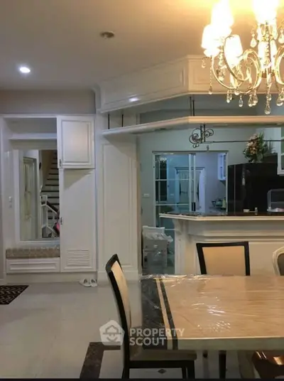Elegant dining area with chandelier and modern kitchen in open layout