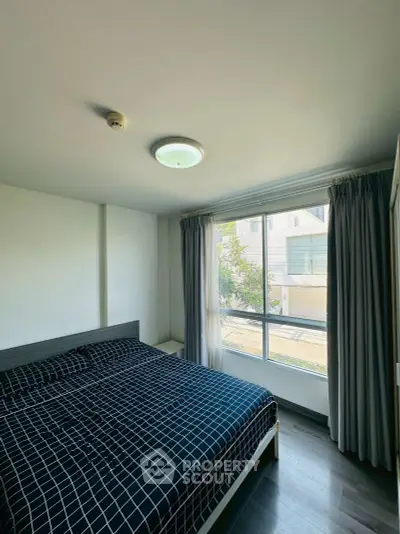 Cozy bedroom with large window and modern decor in a bright apartment.