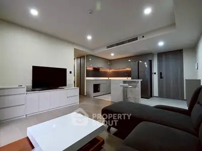 Modern open-layout living room with sleek kitchen, stylish furniture, and ambient lighting in a contemporary apartment.