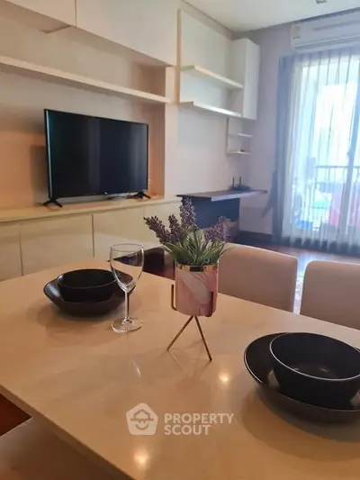 Modern living room with stylish dining setup and TV, featuring elegant decor and natural light.