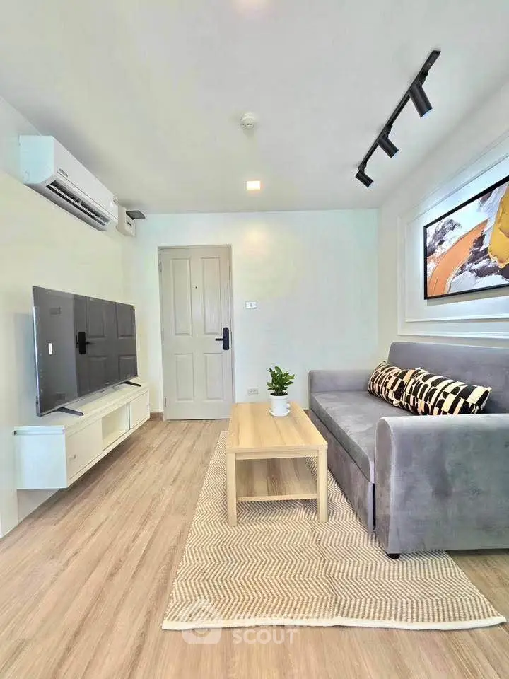 Modern living room with sleek design, featuring a cozy gray sofa, stylish TV setup, and elegant decor.