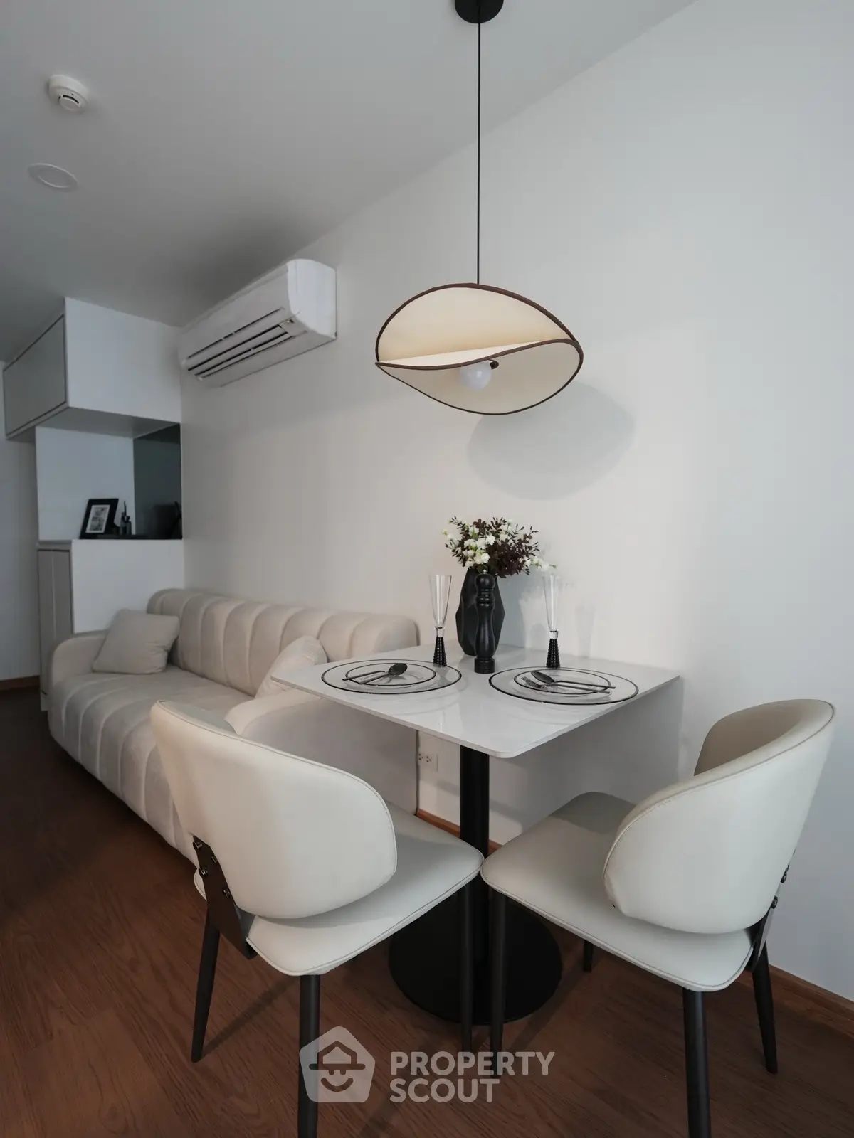 Modern living room with stylish dining area and cozy sofa, featuring elegant lighting and wooden flooring.
