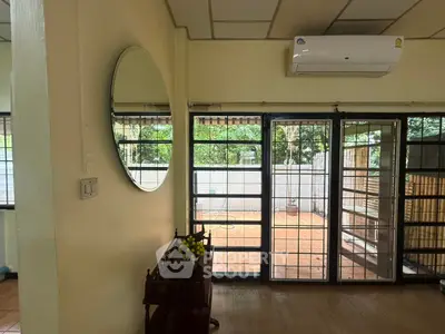 Spacious living room with large windows and garden view, featuring air conditioning and elegant decor.