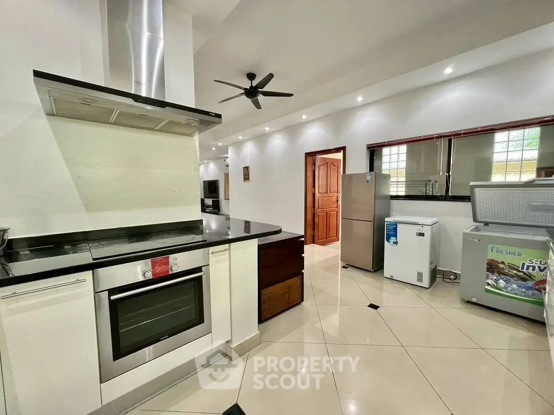 Modern kitchen with sleek appliances and open layout, featuring oven and ample storage space.