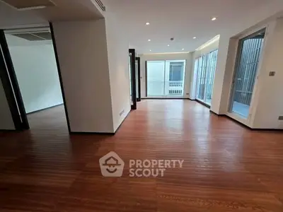 Spacious modern living room with wooden flooring and large windows for natural light.