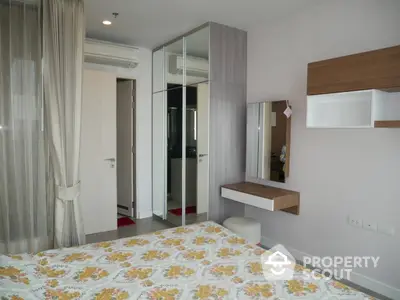 Cozy bedroom with modern furnishings, mirrored wardrobe, and ample natural light, perfect for urban living.