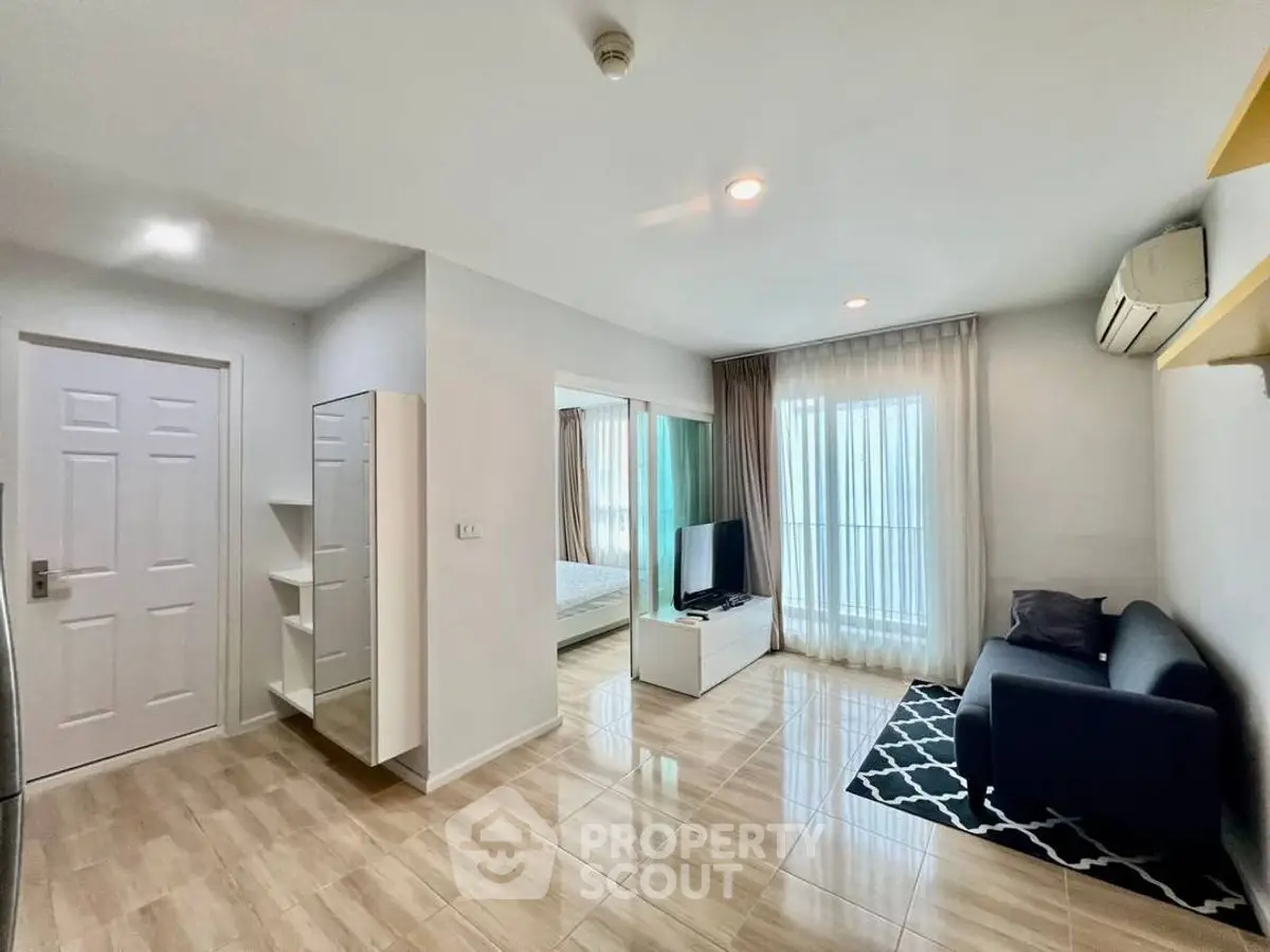Modern living room with sleek design and natural light, featuring a cozy sofa and TV setup.
