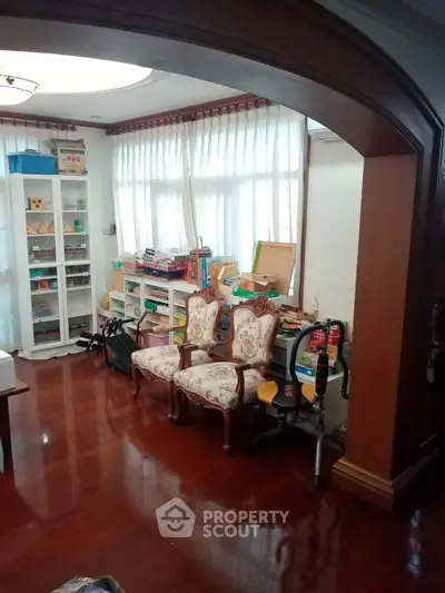 Charming living room with elegant wooden flooring and classic furniture, perfect for cozy family gatherings.