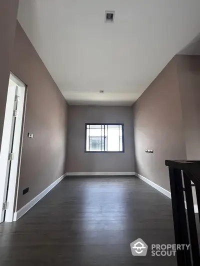 Spacious and modern living room with elegant dark hardwood flooring and neutral wall colors, offering a blank canvas for personalized decor.