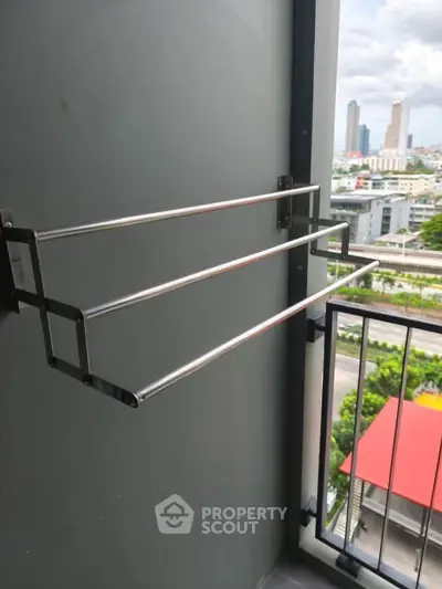 Compact balcony with a sleek metal drying rack and cityscape view, perfect for urban living.