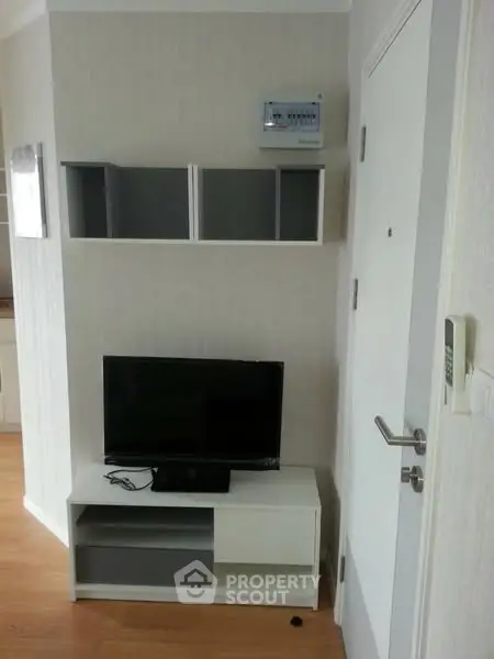 Modern apartment interior with TV unit and wall shelves, showcasing minimalist design.