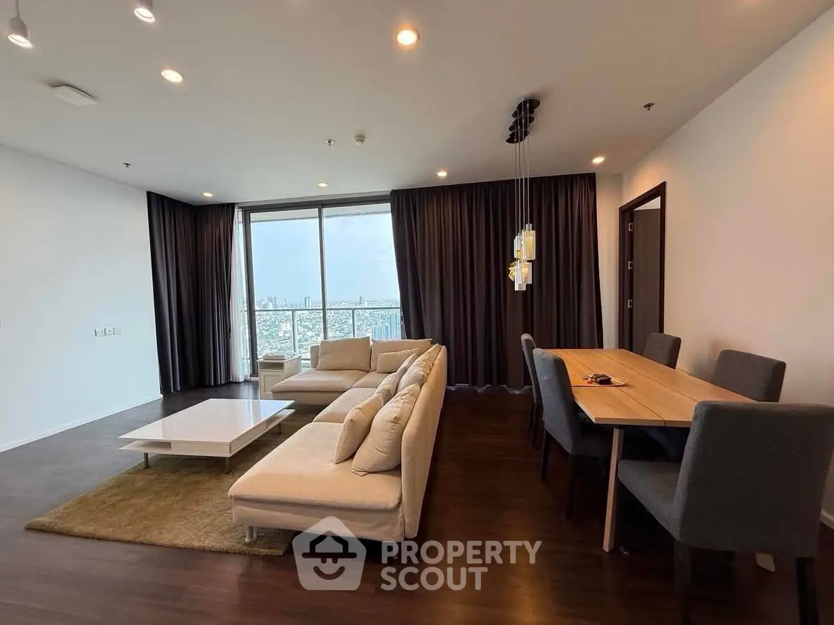 Spacious modern living room with large windows and elegant dining area, offering stunning city views.