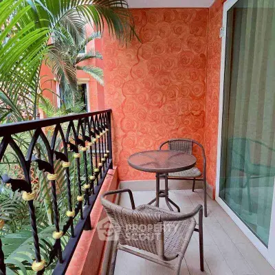 Charming balcony with vibrant orange walls and cozy seating overlooking lush greenery.