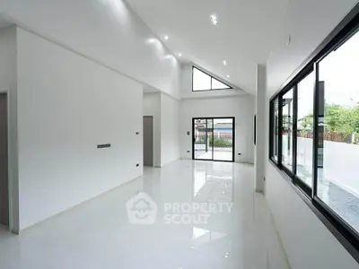 Spacious modern living room with high ceilings and large windows offering natural light and outdoor views.