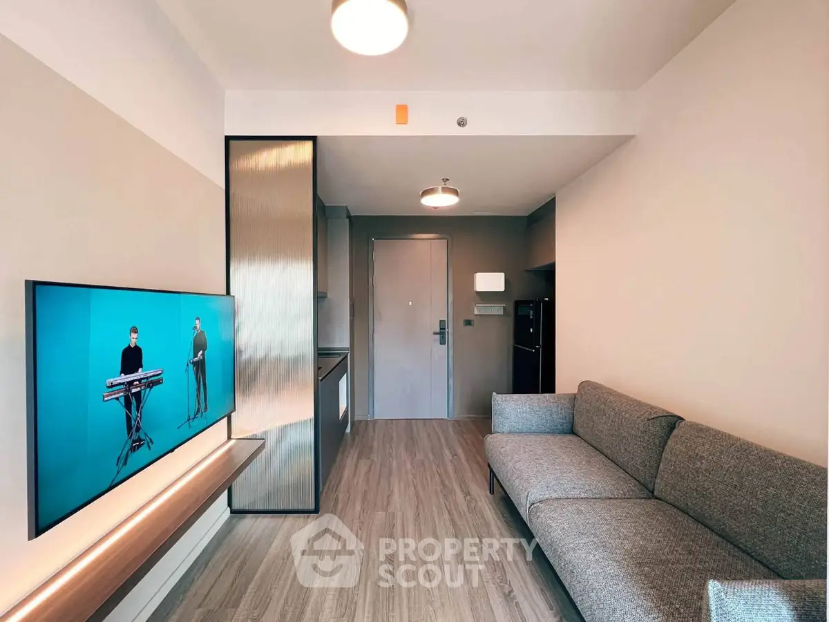 Modern living room with sleek design, featuring a cozy gray sofa and wall-mounted TV, perfect for relaxation.