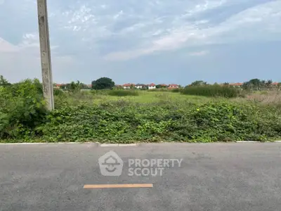 Expansive land plot with potential for development, surrounded by greenery and distant residential views.