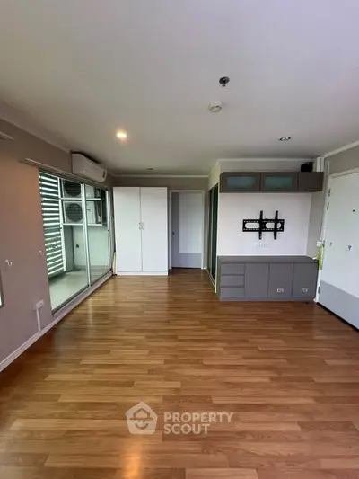 Spacious modern living room with wooden flooring and balcony access in a stylish apartment.