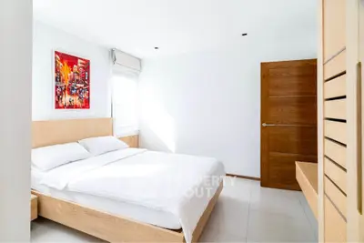 Bright and modern bedroom with wooden furniture and vibrant artwork.