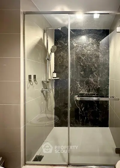 Luxurious modern bathroom with sleek glass shower enclosure and elegant dark marble accent wall.